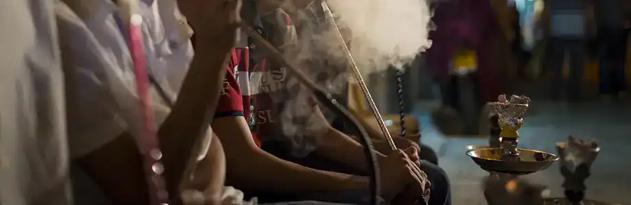 Closeup of hands of people holding hookah hoses